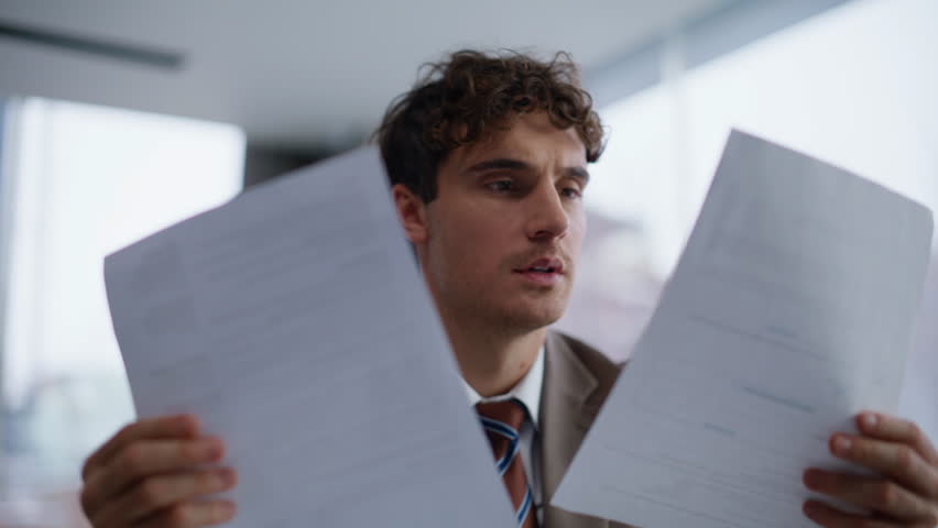 Hands typing computer keyboard at office closeup. Smiling lawyer looking papers comparing information on graphs sitting laptop table workplace. Focused manager working with documents alone indoors
