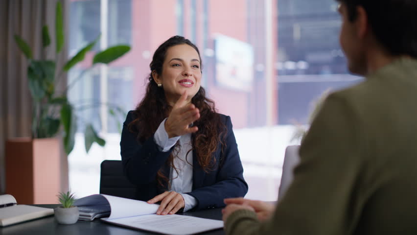 Smiling sales agent talking client giving pen for signing agreement at office portrait. Casual young man customer putting signature concluding partnership shaking hands in panoramic room. Deal concept