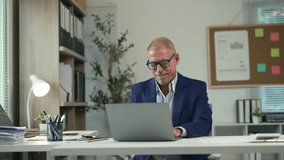 Experienced professional businessman typing on laptop while analyzing documents at workplace, demonstrating focused productivity in corporate environment - Powered by Shutterstock - Get 15% off with code: PIKWIZARD15