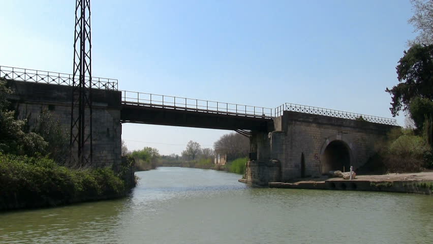 Vessel sails on the canal under the bridge in town