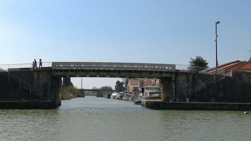 Vessel sails on the canal under the bridge in town