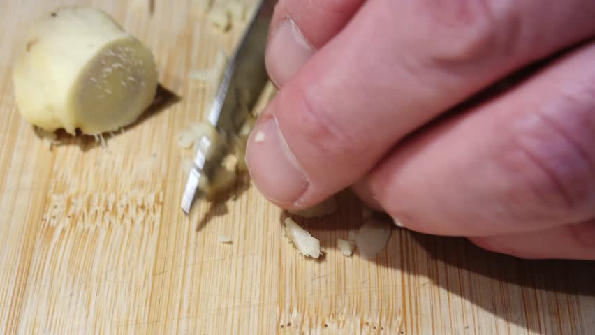 Zagreb, Croatia A man chops fresh ginger on a wooden cutting board. 