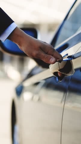 Vertical Format Video of Businessman dressed in business walks to parked car. Man getting into his car and preparing to drive. Confident businessman sitting into his own car