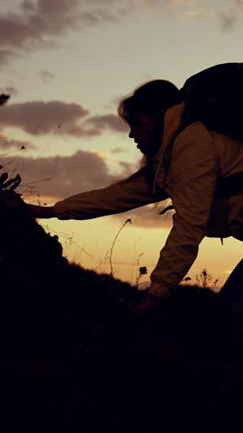 Silhouette of woman climber with backpack against sky, climbing to top of hill. Victory success in business. Hiker. Traveler woman climbs to top of rock. Striving for success, achievement in business