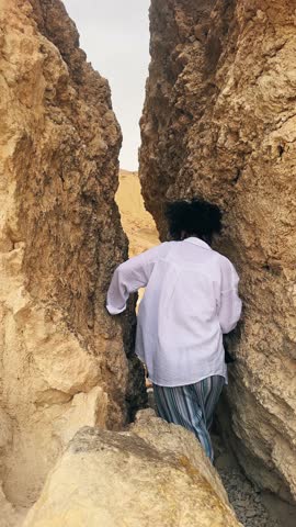 Woman walk exploring a narrow rock passage in the Chebika oasis in Tunisia