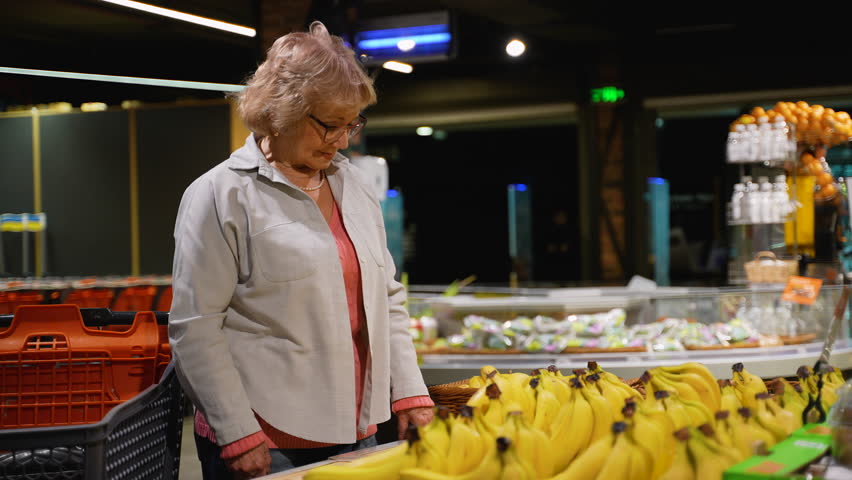 Senior Woman Selecting Ripe Bananas at Grocery Store