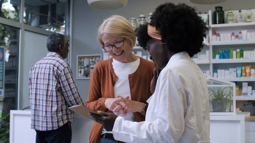 Friendly pharmacist assisting a mature customer with her prescription, providing helpful advice and information
