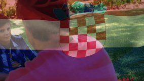Sitting on grass, child holding Croatian flag with animation overlay outdoors. Patriotism, childhood, nature, celebration, heritage, national pride - Powered by Shutterstock - Get 15% off with code: PIKWIZARD15