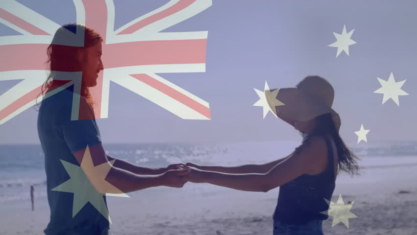 On beach, man and woman holding Australian flag, smiling and having fun. Vacation, holiday, patriotism, celebration, coastline, couple