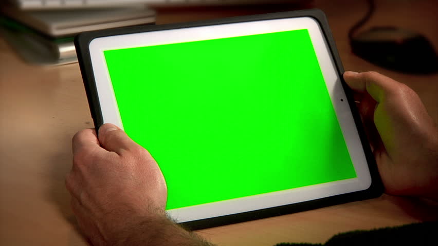 A man uses a tablet PC at his desk.  Chroma key screen for placement of your own