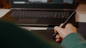 Woman works diligently in her home studio, skillfully retouching images on a graphics tablet while using her laptop for editing. Her focus and creativity are evident. - Powered by Shutterstock - Get 15% off with code: PIKWIZARD15