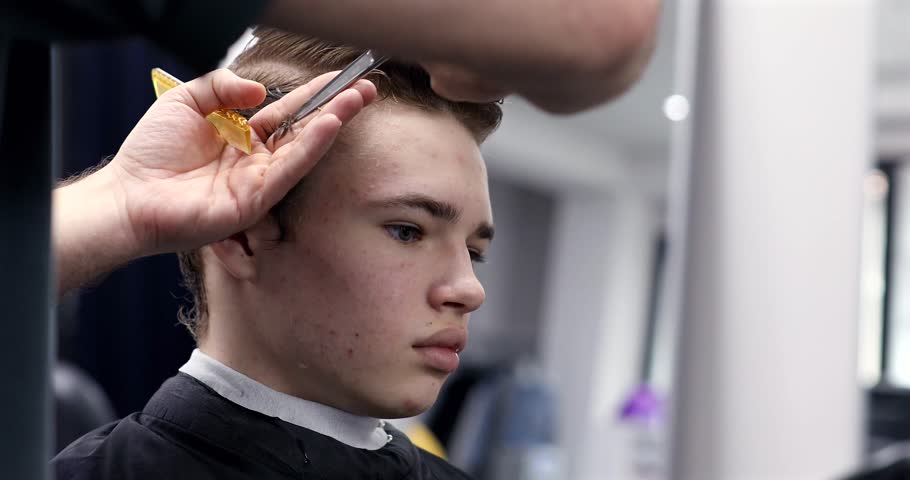 Man getting haircut at barber shop. Male hairstylist at work. 