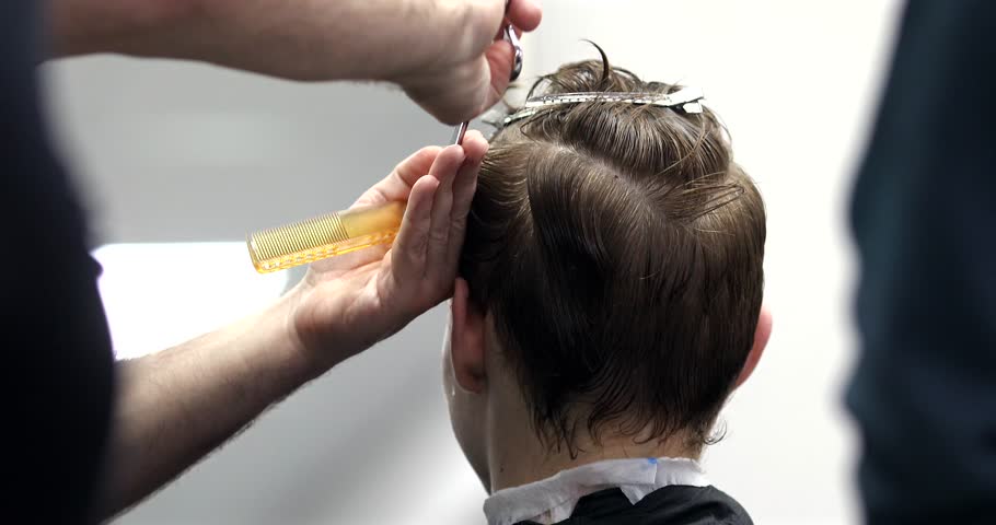 Man getting haircut at barber shop. Male hairstylist at work. 