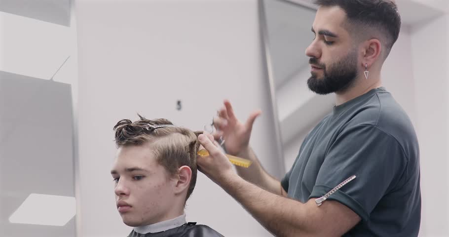 Man getting haircut at barber shop. Male hairstylist at work. 