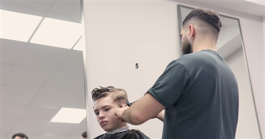 Man getting haircut at barber shop. Male hairstylist at work. 