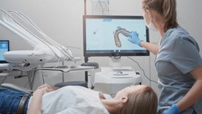 Girl doctor dentist demonstrates a 3D model of teeth on a touch monitor, rotates her hands. Dental consultation in the clinic, diagnostics. Jaw scan, digital imprint, medical digital technology. - Powered by Shutterstock - Get 15% off with code: PIKWIZARD15