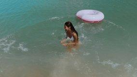 A hilarious super slow-motion video of a woman in a white bikini jumping into clear water, aiming for a pink donut inflatable but missing it. Perfect for fun, summer, and blooper themes.  - Powered by Shutterstock - Get 15% off with code: PIKWIZARD15