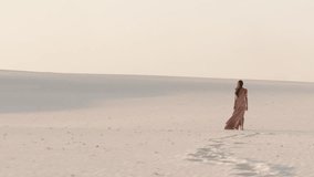 A stunning woman walks gracefully across expansive white sand dunes, leaving a trail of footprints. The epic scene features soft lighting, vast landscapes, and slow-motion elegance, ideal for - Powered by Shutterstock - Get 15% off with code: PIKWIZARD15