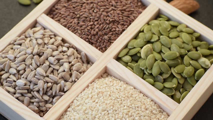 Sunflower, pumpkin, flax and sesame seeds in a wooden box as ingredients for making vegetarian and vegan food