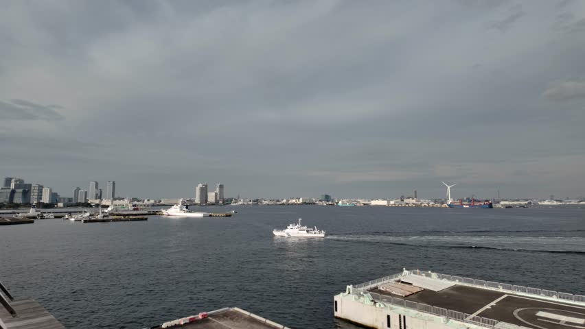 View of Yokohama Bay with patrol boat cruising and city skyline in background, seen from Osanbashi Pier