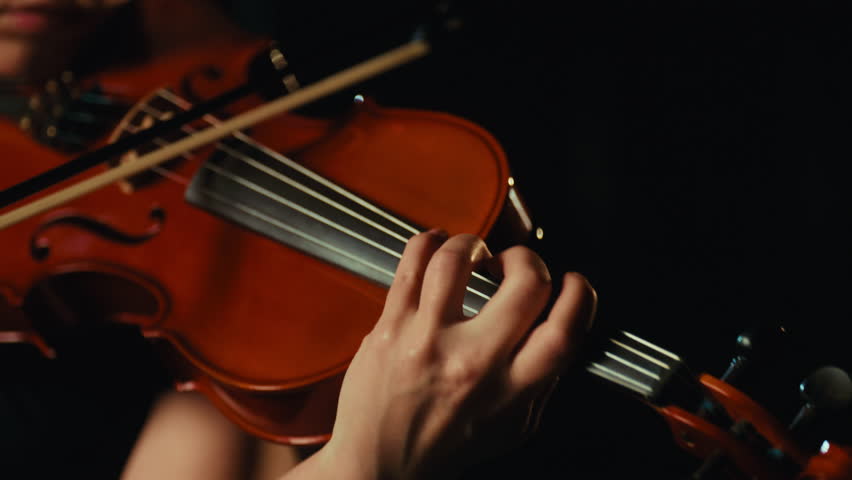 Closeup view of female violin player hand on violin, lady playing classic music . Details view, classical music concert, inspired woman musician performing modern melody by ancient musical instrument