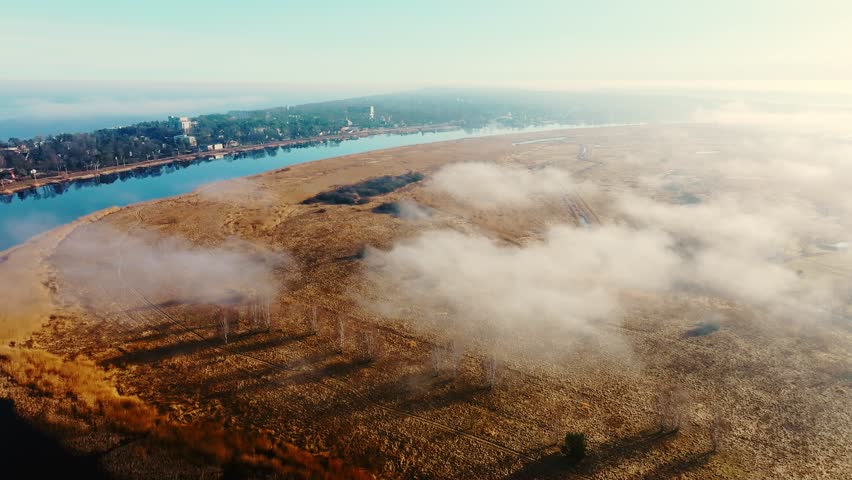 Soft mist floats over Jūrmala, Lielupe River as sun rises, Baltic Sea horizon