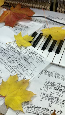 music studio scene - sheets of music notes among autumn maple leaves lie on the piano keyboard, ukulele, microphone