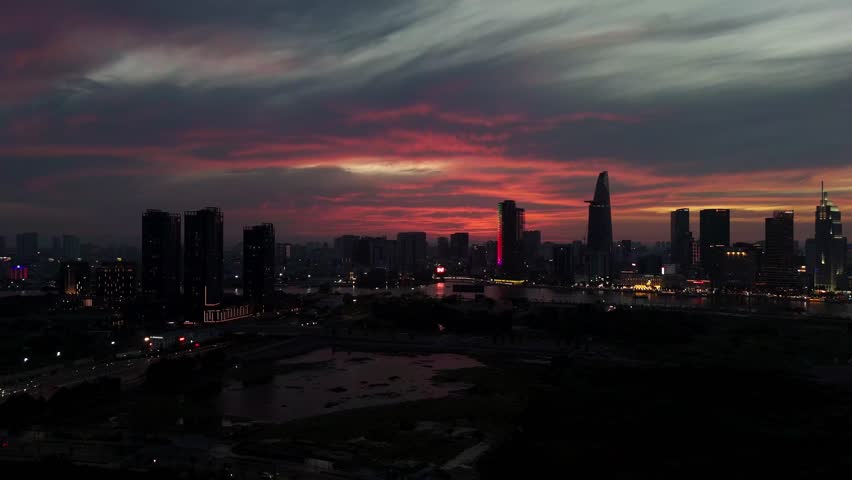 A mesmerizing aerial view of Ho Chi Minh City's skyline at dawn, with the city's towering buildings silhouetted against a stunning red-orange sky