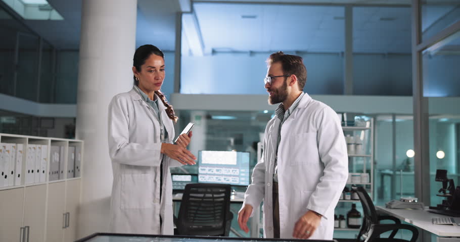 Scientist, research or discussion with tablet in lab for pharmaceutical review, medical comparison or innovation. Night, people or interactive display for studying science data, teamwork and results