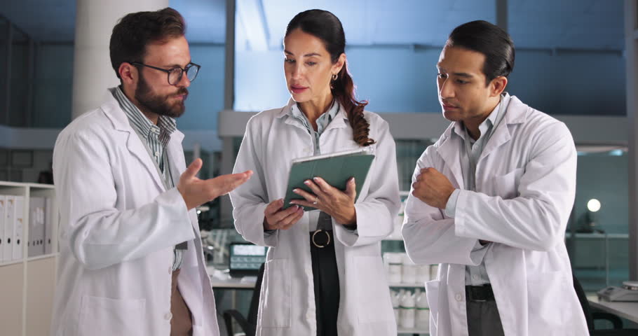 Scientist, people and discussion with tablet in laboratory for pharmaceutical planning, medical research and feedback. Night, teamwork and clinical analysis of science data and experiment results