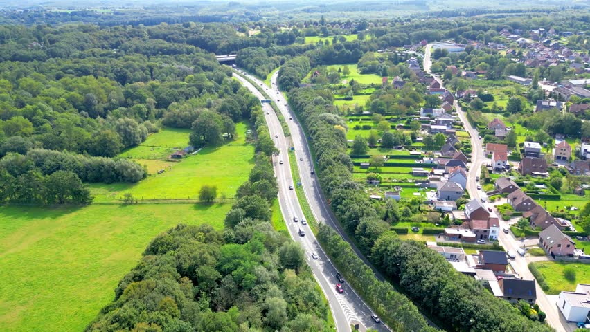 E429, Halle, Vlaams Brabant, Belgium, September 8th, 2024, A stunning aerial perspective of a highway meandering through vibrant landscapes and residential areas.