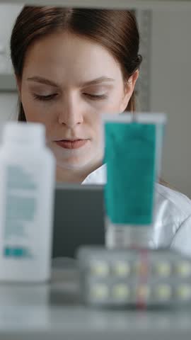 The girl pharmacist conducts an audit of medical products in the pharmacy. Caucasian woman with an electronic tablet checks the presence of drugs creams and tablets on the shelf in the pharmacy