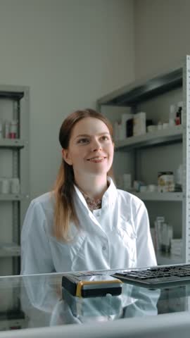 Customer picks up order in white package from female pharmacist at pharmacy. An adult man came for his order with medication and paid for it with a credit card. Vertical shot.