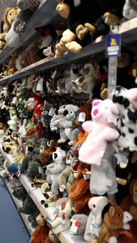Vertical screen: Aisle filled with a colorful variety of plush toys in a toy store. From koalas to penguins, the shelves are packed with soft animals ready to bring joy to children.

