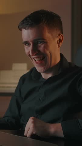 The mother-of-one rejoices in writing an angry comment on social media. Interior of modern cozy apartment in the evening. A man spoils the mood of content creators, dislike. Vertical shot.