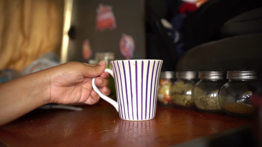 A slow-motion of Brazilian woman in black t-shirt, taking a sip of coffee, enjoying her drink