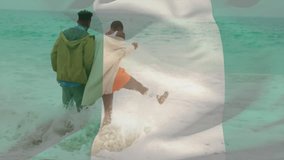 Walking in ocean waves, couple with flag animation overlay in background. Beach, vacation, holiday, romantic, togetherness, patriotism - Powered by Shutterstock - Get 15% off with code: PIKWIZARD15