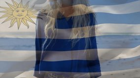 Holding Uruguay flag, smiling woman at beach with animation overlay. Holiday, vacation, travel, summer, coastline, patriotism - Powered by Shutterstock - Get 15% off with code: PIKWIZARD15