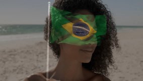 Holding Brazilian flag, person smiling with animation overlay on face at beach. celebration, patriotism, sand, tropical, summer, happiness - Powered by Shutterstock - Get 15% off with code: PIKWIZARD15
