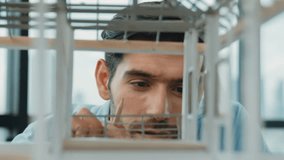 Closeup of young caucasian skilled architect engineer focusing on checking the house model structure with confident. Male worker looking at house construction. Creative design concept. Tracery - Powered by Shutterstock - Get 15% off with code: PIKWIZARD15