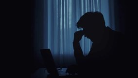 A silhouette of an individual typing on a laptop in a dimly lit room, creating a mysterious atmosphere. - Powered by Shutterstock - Get 15% off with code: PIKWIZARD15