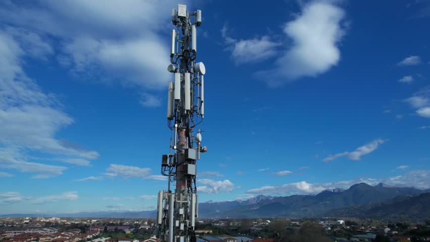Video of a cell phone signal repeater with antennas, on a metal pole, against a blue sky and clouds. 