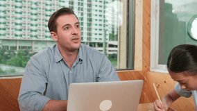 Happy caucasian teacher and diverse student exchange idea while siting on table with paper. Skilled instructor using laptop to analyze data while student taking a note or writing idea. Edification - Powered by Shutterstock - Get 15% off with code: PIKWIZARD15