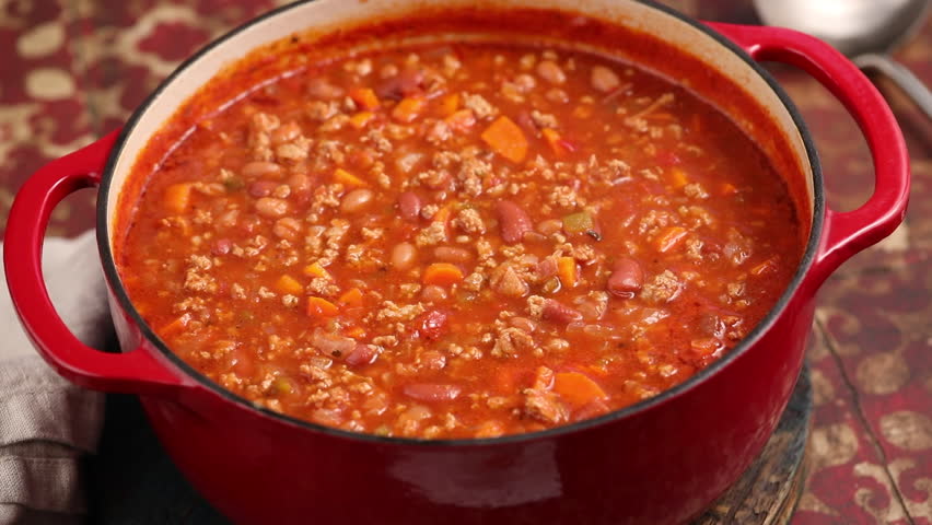 Beef chili in a pot close up, scooping some up with a ladle