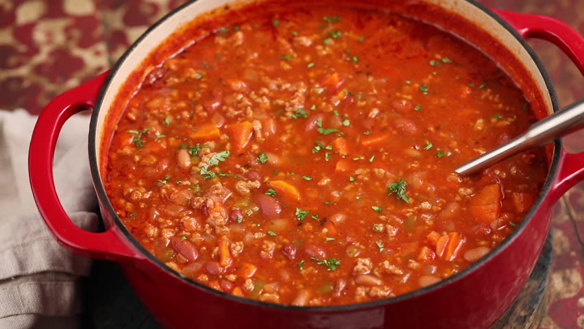 Beef chili in a pot close up, scooping some up with a ladle