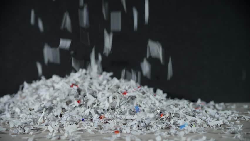 Shredded office paper falling onto a table, creating a pile. Slow motion