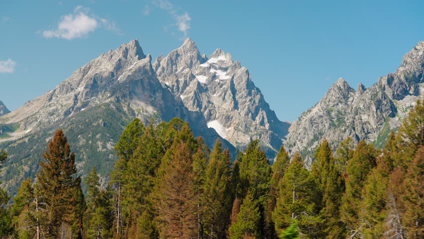 Tall trees surround stunning mountain peaks, creating a perfect setting for a summer adventure filled with breathtaking views, outdoor exploration, and natural beauty.