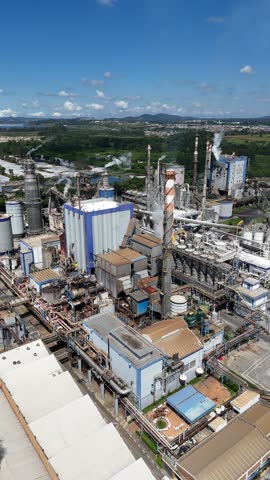 Aerial vertical view of a pulp and paper industry, showcasing steam emissions, chimneys, boilers, and industrial equipment in full operation