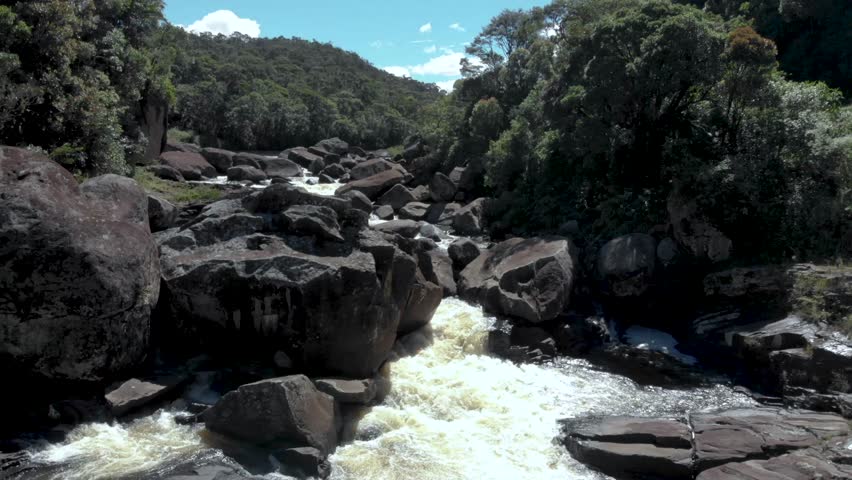 A drone footage of Andriamamovoka Falls flowing on rocks and surrounded by green lush vegetation
