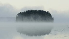 A scenic misty view of the lake and clouds covering lush forest under a gray sky - Powered by Shutterstock - Get 15% off with code: PIKWIZARD15